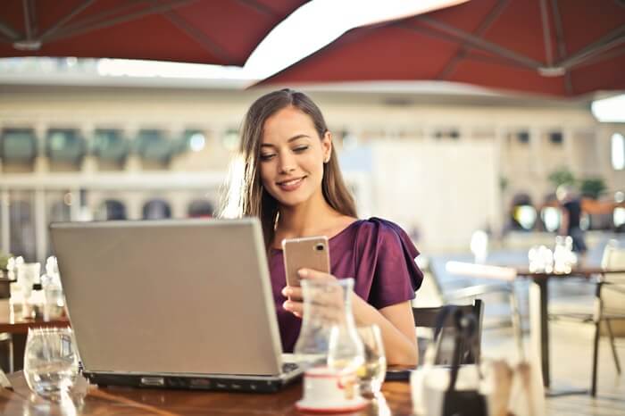 kobieta siedz z laptopem i telefonem przy stoliku