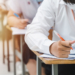 college students writing final examination papers classroom concentratively scaled
