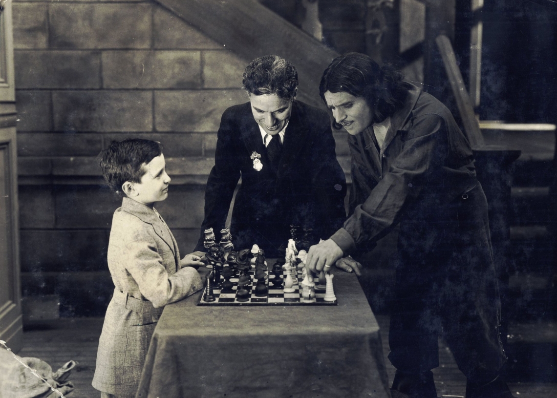 Partia Samuela Reshevsky'ego z aktorem Douglasem Fairbanksem na planie "Trzech Muszkieterów", niemego filmu z 1921 roku. Pojedynkowi odtwórcy roli d'Artagnana z genialnym szachowym dzieckiem z Polski przygląda się Charlie Chaplin.